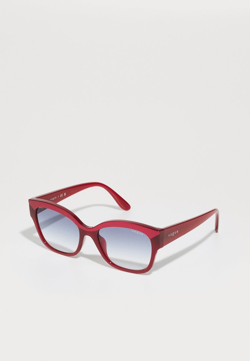 Ochelari de soare roșii din plastic, cu un cadru pătrat, lentile cu gradiente și logo pe sprijin. Textură netedă, design elegant și formă unghiulară.