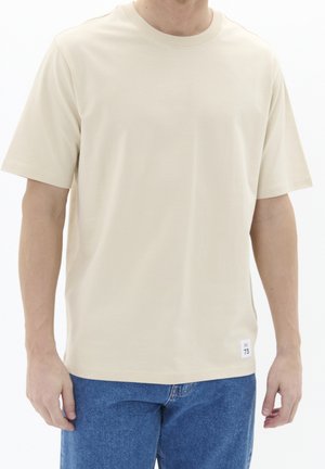 Beige T-shirt met korte mouwen van gladde stof, met een ronde halslijn en een label aan de onderkant met maat- en merkinformatie.