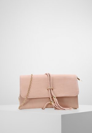 Lichtroze leren clutch met gevlochten band, gouden ketting, tassels en magnetische sluiting op een wit voetstuk tegen een effen achtergrond.