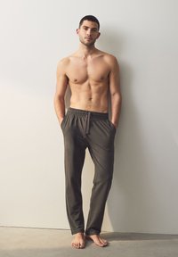Grå, letvægts loungebukser med elastik i taljen og snøre, sidelommer, lige ben, båret af en mandlig model.