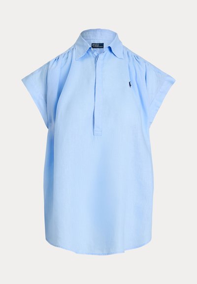 Gaiši zila bezroku blūze ar līkenu apkakli, priekšpuses pogu aizdari un nelielu izšūtu logotipu kreisajā krūtīs.