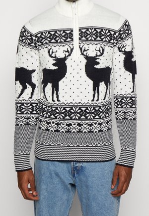 Pull en maille avec demi-fermeture éclair, présentant un schéma de couleurs blanc et bleu marine, des motifs de rennes, des flocons de neige et des accents en maille texturée.