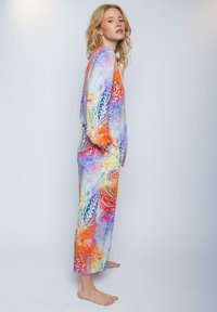 Helle, farbenfrohe Loungebekleidung aus leichter Baumwolle. Mit wirbelnden Mustern in Orange, Blau und Lila. Lockere Passform mit weiten Ärmeln und knöchellang.