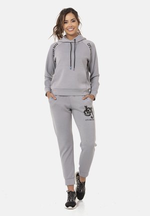 Graue Kapuze mit Logo-Akzenten, Kordeln mit Farbspitzen und passenden Jogginghosen mit Logo-Druck. Weicher Stoff, lässige Passform.