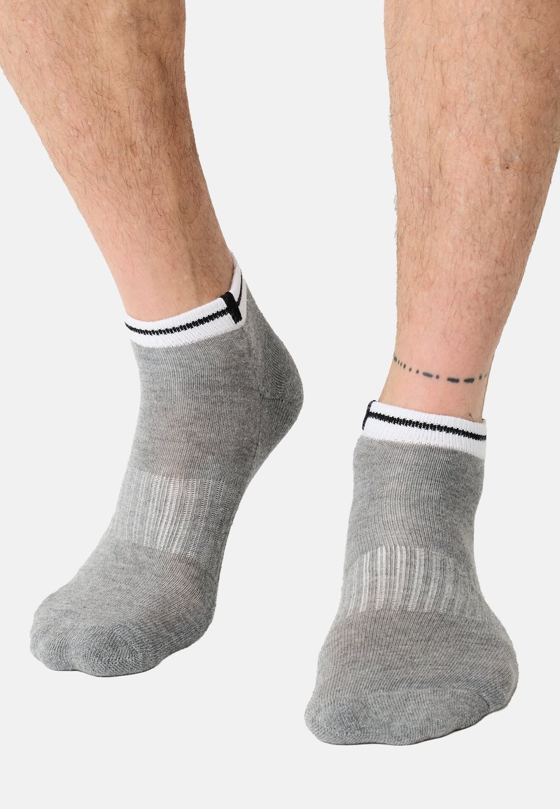 Szare skarpetki do kostki z prążkowaną fakturą, z białym mankietem i czarnym paskiem, dopasowane ciasno wokół kostki.