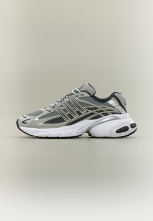 Szary i biały sportowy sneaker z siateczką i syntetycznymi nakładkami, sznurowany, z grubą, wyściełaną podeszwą na neutralnym tle.