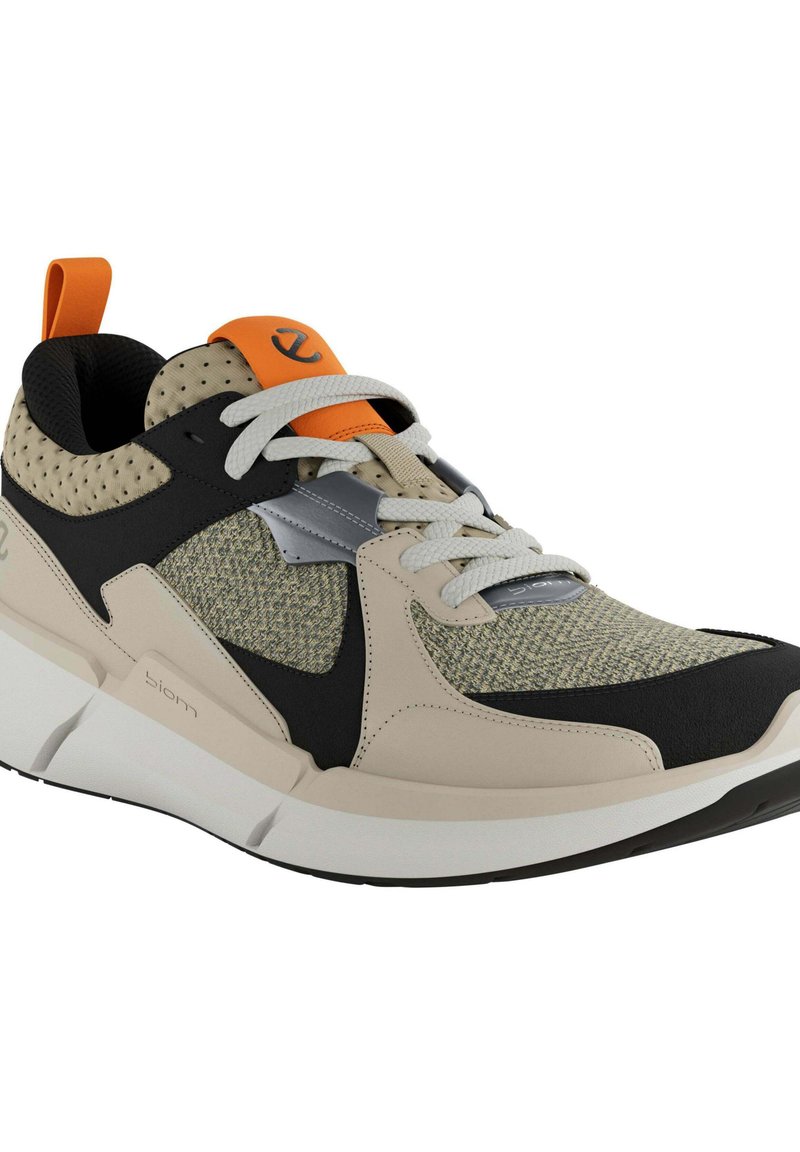 Leichter Sneaker aus beigem und schwarzem Stoff, mit Mesh-Akzenten, strukturierten grauen Einsätzen, weißer Sohle und orangefarbener Schlaufe. Verfügt über symmetrische Schnürung.