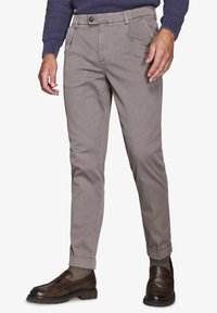 Brune, strukturerede bukser med slim fit, udstyret med knaplukning, sidelommer og opsmøget kant, parret med mørkebrune loafers.