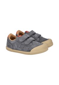 Zapatillas de ante gris con suelas de goma beige, que presentan dos cintas de Velcro, perforaciones en los laterales y acentos rojos del logo en la lengua.