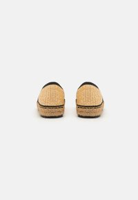 Încălțăminte slip-on din paie țesută, cu un contur negru, având o talpă din iută în stil espadrille și un design cu vârf rotund.