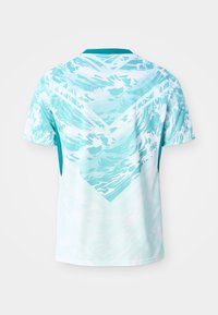 Αθλητικό πουκάμισο με μανίκια κοντά, με ανοιχτογάλανα και λευκά αφηρημένα κυματιστά μοτίβα και μονόχρωμο τυρκουάζ γιακά, εμφανίζεται από πίσω.