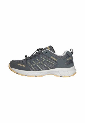 Zapatilla deportiva de malla gris oscuro con acentos beige, suela blanca, bloqueo elástico de cordones y marca "SKOGAN" en el lateral y la lengüeta.