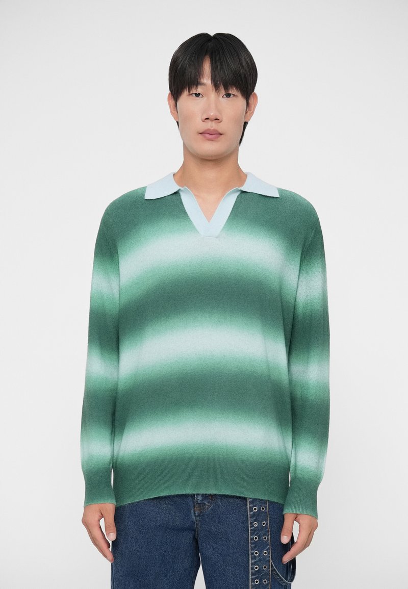 Green gradient sweater with a light blue collar, featuring a v-neck, long sleeves, and a soft texture. Worn over denim jeans.