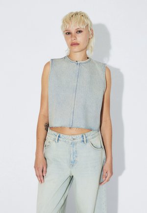 Lichtblauw cropped denimvest met een ronde halslijn en een rafelige zoom, gecombineerd met lichtblauwe hoge taille jeans met zijzakken aan de voorkant.