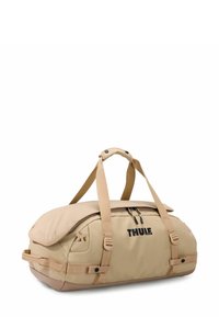 Sac de voyage beige avec un extérieur en tissu doux, forme arrondie, fermeture éclair, poignée supérieure et bretelles ajustables. Présente un logo sur le côté.
