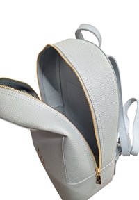 Zaino in pelle grigio chiaro con una finitura testurizzata, zip dorata e una sola maniglia. L'interno include una tasca e un design spazioso.