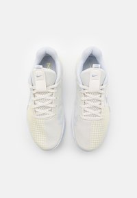 Buty sportowe Nike w jasnoszarej siateczce z białymi i żółtymi akcentami. Posiadają sznurowanie oraz wyściełany kołnierz zapewniający komfort.