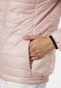 Giacca isolante rosa chiaro con tasca con zip, tessuto trapuntato, polsini elasticizzati e design elegante. Tessuto liscio con una finitura morbida.