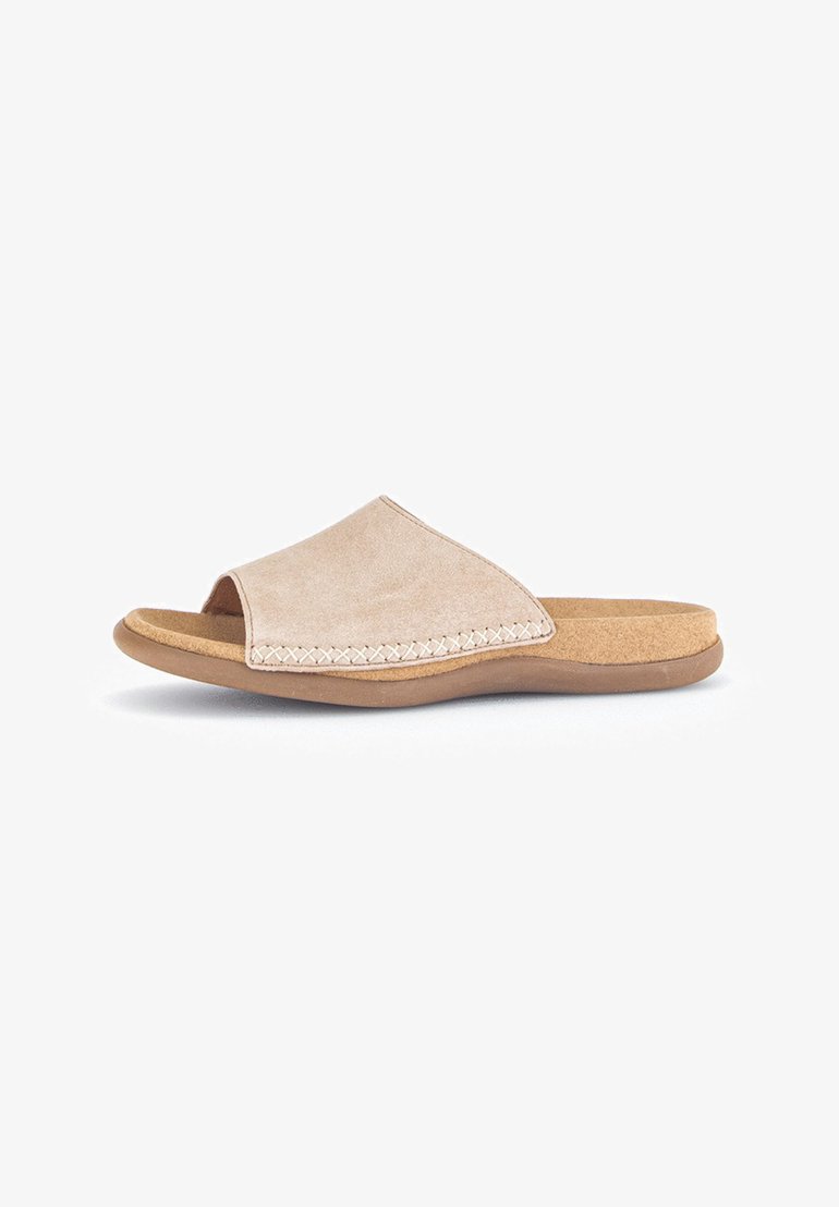 Beige suede slip-on sandal with an open toe, curved design, and stitched detailing along the edge. Cork footbed for comfort.