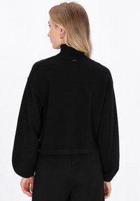 Zwart cropped sweater met een hoge halslijn, lange ballonmouwen en een zachte textuur. Heeft een eenvoudig ontwerp zonder versieringen.