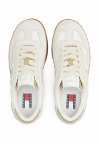 Sneaker bianchi con accenti beige, caratterizzati da un mix di textures lisce e scamosciate, lacci piatti e un logo sulla linguetta. Suola in gomma.