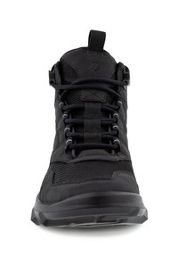 Chaussure de sport montante noire avec des panneaux en mesh, une semelle épaisse, une languette à boucle et des lacets ronds passant à travers des œillets en tissu.