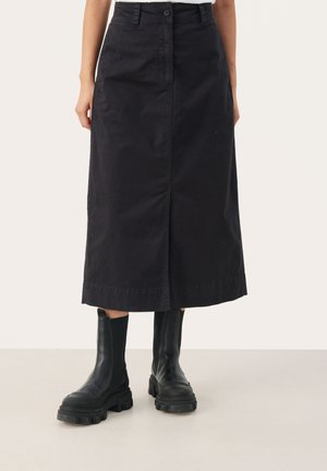 Black cotton mid-length skirt with a front button closure and side slit, paired with chunky black ankle boots. Smooth texture and simple design.
