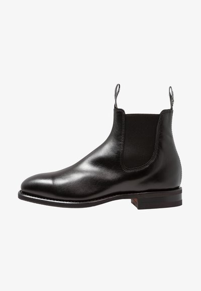 Black leather Chelsea boot with elastic side panels, smooth finish, rounded toe, and a low stacked heel. Features pull tabs for easy wear.