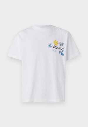 T-shirt en coton blanc avec une broderie florale colorée en jaune, bleu et vert sur la partie gauche de la poitrine. Manches courtes, encolure ronde.