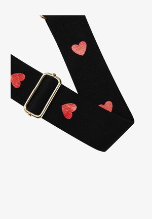 Sangle en tissu noir réglable avec des motifs de cœurs rouges et une boucle en métal doré, présentée sur fond blanc.