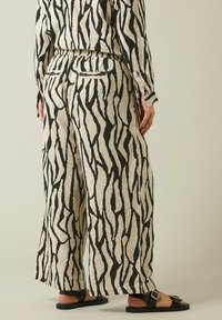 Broek met een zwart en beige abstract patroon, gemaakt van textuurstof, met een elastische tailleband en twee achterzakken.