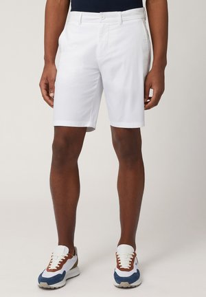 Shorts bianchi in cotone dal design semplice, con chiusura a bottone, tasche laterali e vestibilità dritta, abbinati a sneakers sportive multicolori.