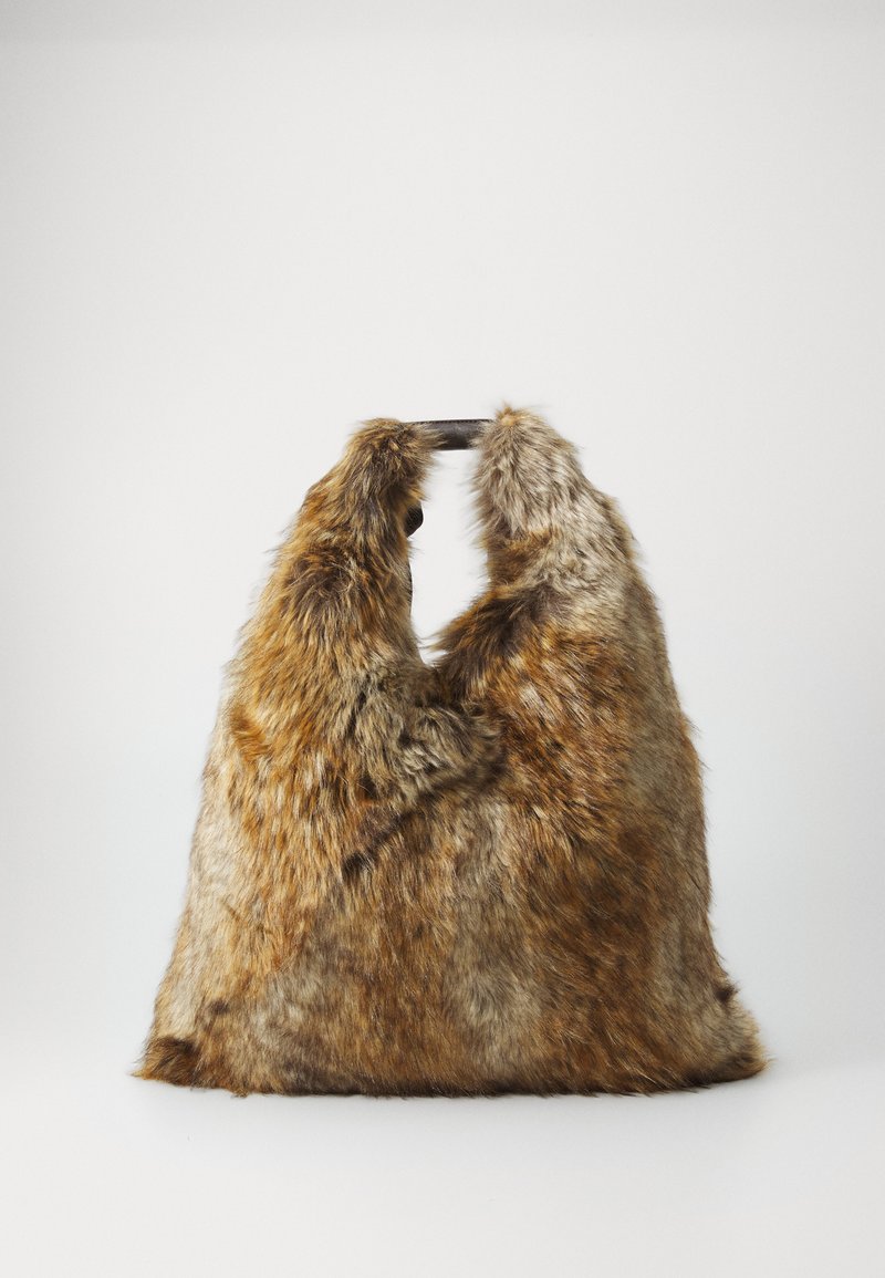 Hnědá a šedá taška z umělé kožešiny s krátkými černými ušima, stojící vzpřímeně na jednoduchém bílém pozadí.
