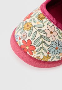 Suprafață din material cu model floral în culori pastelate, cu o talpă din cauciuc texturat roz, având un vârf rotund și un finisaj neted pe margini.
