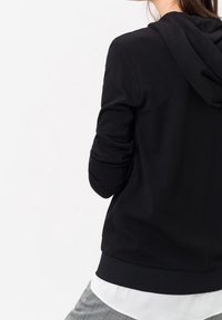 Black hoodie featuring a relaxed fit, long sleeves, and a drawstring hood. Soft texture and ribbed hem detail for a comfortable wear.