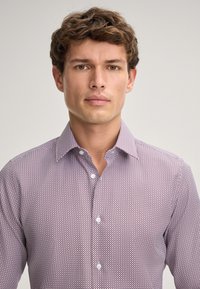 Camicia abbottonata con un piccolo motivo geometrico in viola e bianco, colletto corto e bottoni bianchi. Texture del tessuto liscia.
