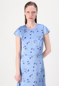Light blue dress with short sleeves, featuring a floral pattern in purple and green. Smooth texture, round neckline, and fitted design.