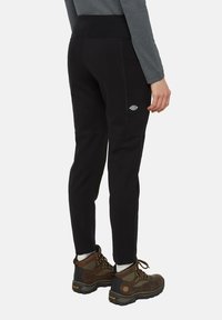 Zwarte lichtgewicht wandelpants met een taps toelopend ontwerp, zijzakken en een stretchy tailleband. Gecombineerd met bruine wandelschoenen.