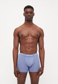 Plave bokserice s uzorkom i mekanim elastičnim pojasom na kojem se nalazi logo "Levi's"; izrađene od rastezljivog materijala za udobnost.