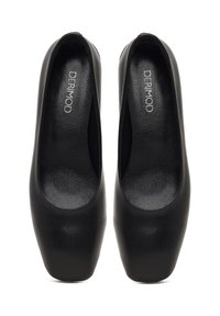 Chaussures noires en cuir à enfiler avec un bout rond, texture lisse et design minimaliste. Nom de la marque "DERIMOD" visible à l'intérieur.