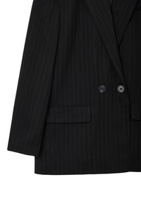 Blazer nero a righe con design doppiopetto, due tasche frontali e due bottoni neri. Tessuto liscio con una silhouette strutturata.