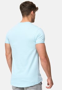 Camiseta de manga corta azul claro con cuello redondo, hecha de una suave mezcla de algodón. Presenta un corte recto y un detalle mínimo.