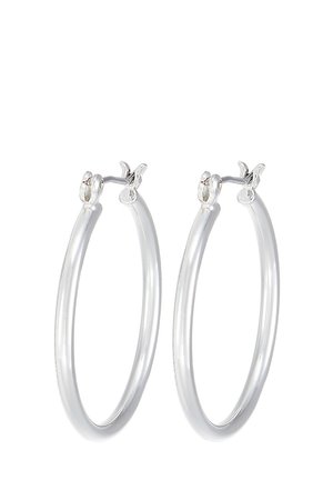 Paire de boucles d'oreilles créoles argentées de taille moyenne avec fermoirs à charnière sur fond blanc.