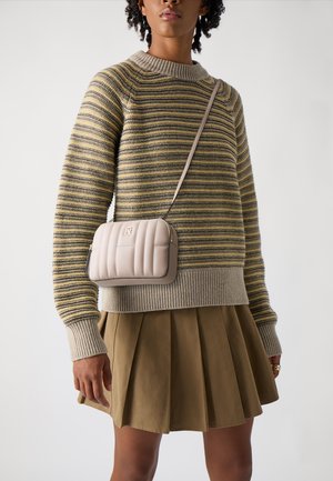 Randig tröja i beige och oliv, med en ribbad krage. En krämfärgad, vadderad axelväska med en guldlogotyp. Olivgrön, plisserad kjol.