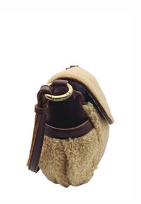 Sac en shearling tan avec une bandoulière en cuir marron ; forme arrondie, accents en métal doré. La fermeture à rabat est douce et texturée.