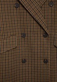 Doppeltreif brauner und grüner karierten Blazer, ausgestattet mit strukturiertem Stoff, braunen Knöpfen und einer Tasche auf der linken Seite.