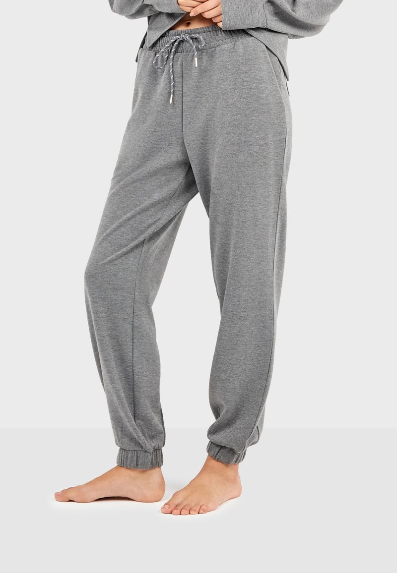 Pantalones jogger de algodón gris con cinturilla ajustable, puños entallados y bolsillos laterales, que presentan una textura suave y un ajuste relajado.