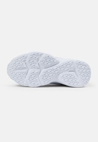 Semelle d'une chaussure de sport en matériau en caoutchouc blanc texturé, avec un motif de grip composé de formes triangulaires et circulaires pour l'adhérence.