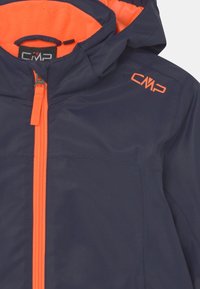 Giacca impermeabile blu navy con zip arancione e fodera interna. Presenta il logo CMP sul petto, cappuccio regolabile e una texture liscia.
