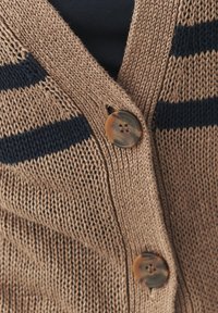 Beige knitted cardigan with navy stripes, featuring a V-neck, textured pattern, and a rounded brown button detail on the front.